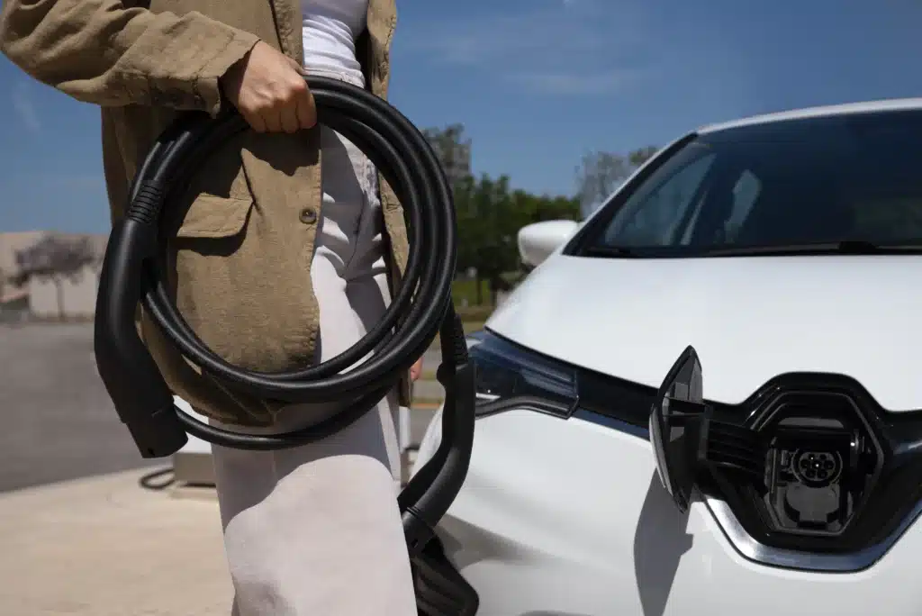 Vue latérale d'une personne tenant le câble de charge pour véhicule électrique